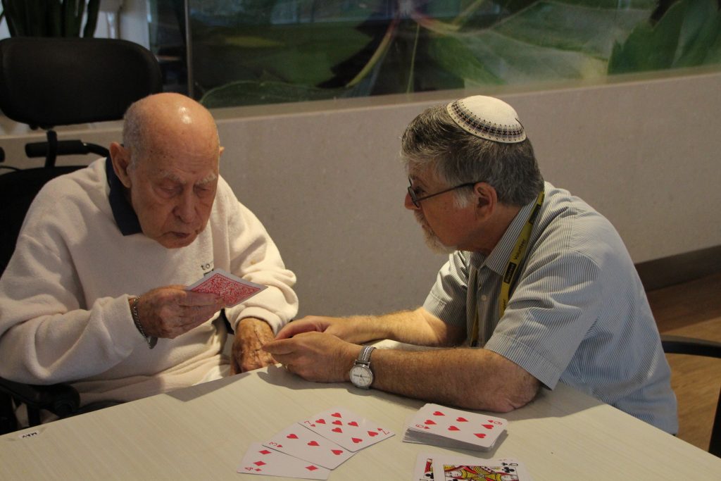 A volunteer plays cards with a Baycrest resident during a PLEASE Program session.