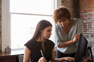 A younger woman is helped by her mentor.