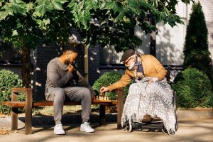 young man playing chess with older adult man in a park