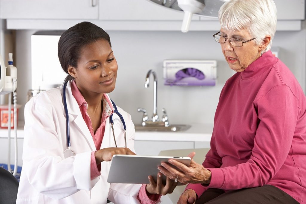 Smiling female doctor showing elderly woman her charts
