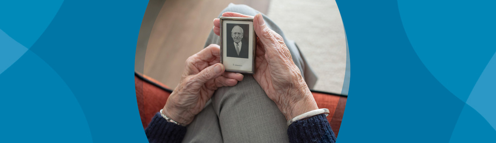 Elderly pair of hands holds a photo of a loved one (a man) who has passed.