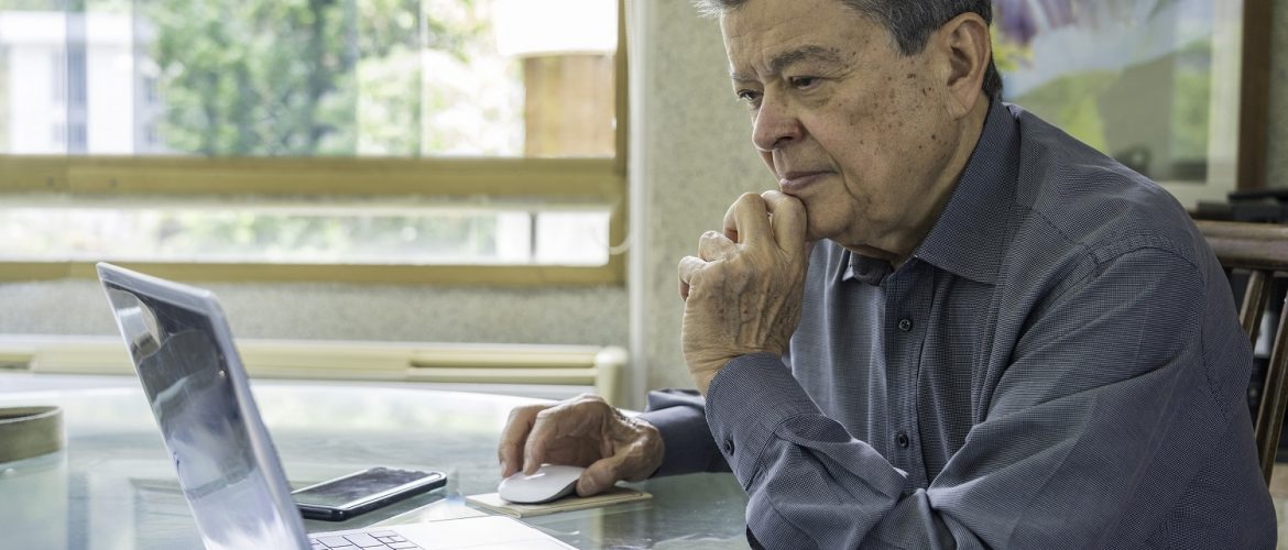 Latinx senior man working at home office with laptop computer.