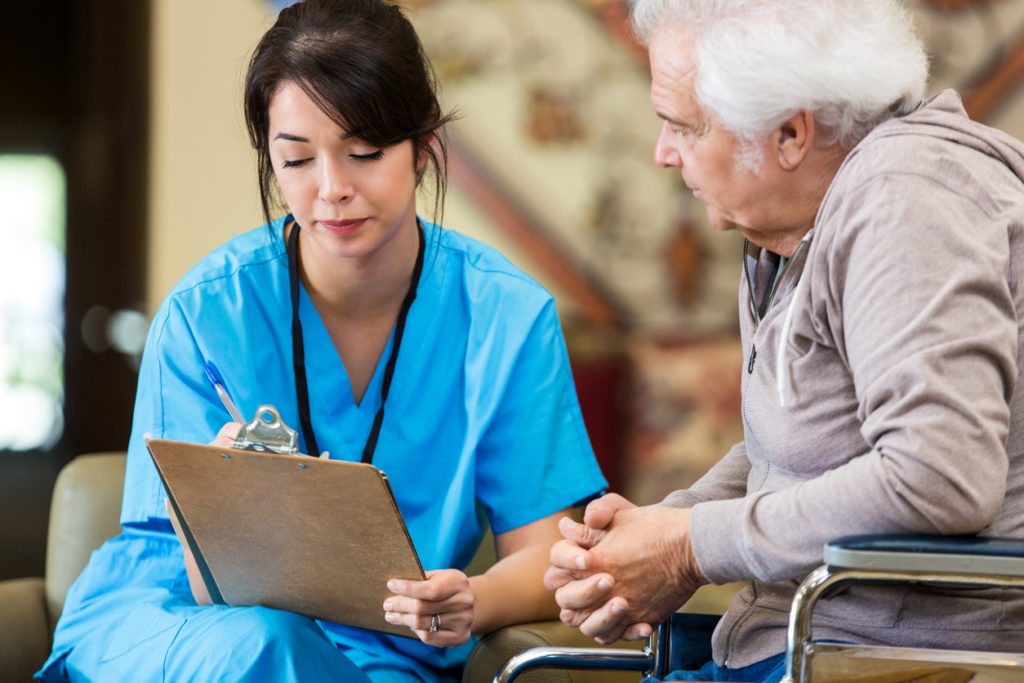 Nurse reveiws patient information with senior man