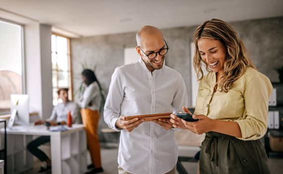Businessman and businesswoman smiling looking at phone