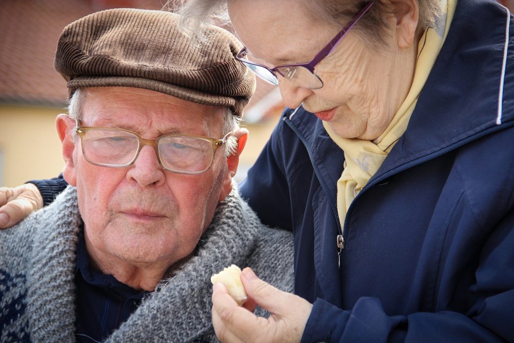 A elderly woman with her arm around an elderly man