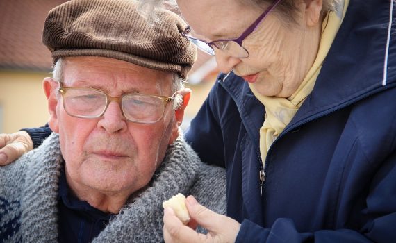 A elderly woman with her arm around an elderly man