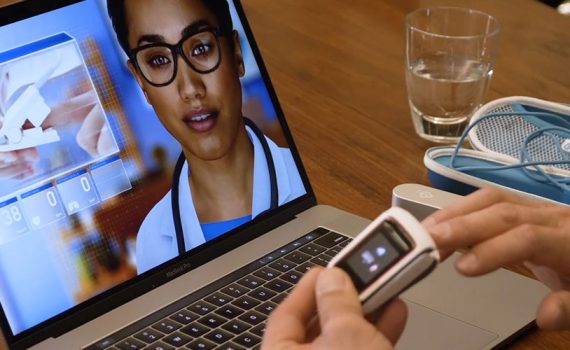 An artificial human is shown on a laptop screen while a person uses an oximeter.