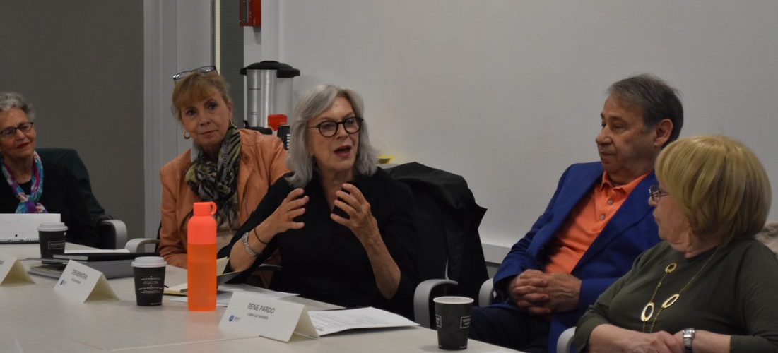 A woman talking around a table with older adults.