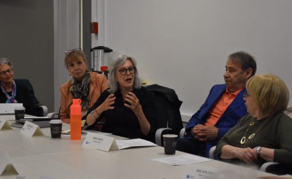 A woman talking around a table with older adults.