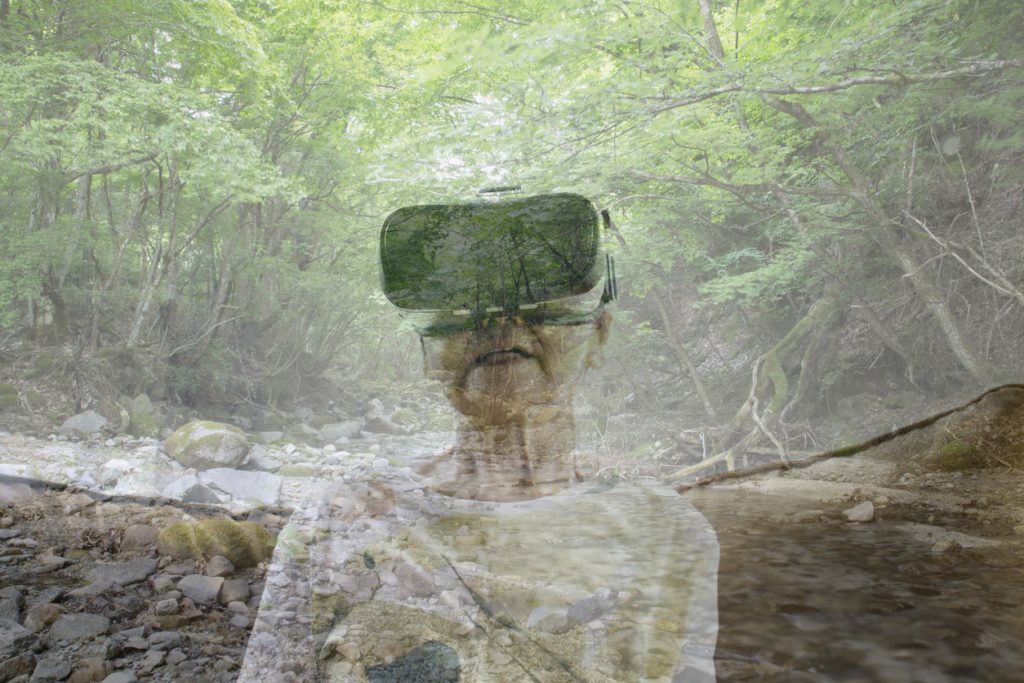 Senior woman wearing a virtual reality headset and viewing mountain stream in a virtual reality world