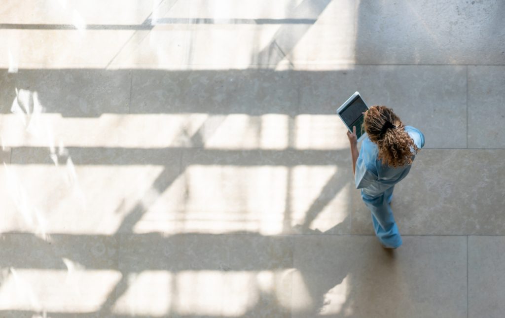High angle view of nurse walking around hospital while looking at a medical chart on tablet
