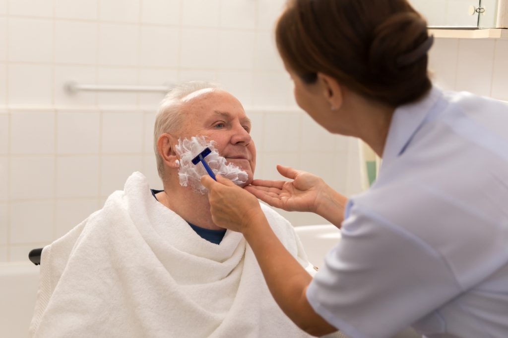 Caregiver helping a senior man with grooming