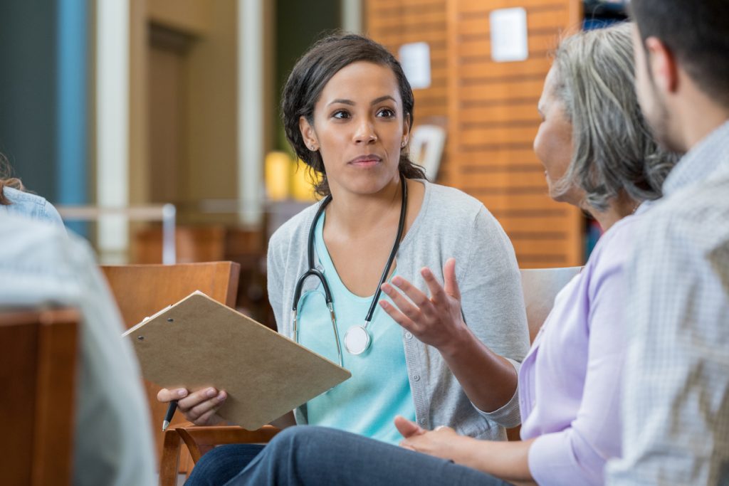 Point-of-care worker talks with a senior and other family members