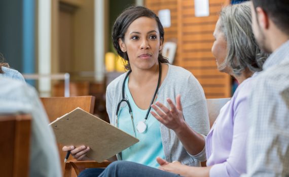 Point-of-care worker talks with a senior and other family members