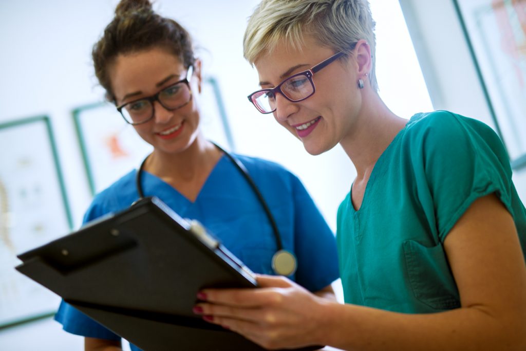Two point-of-care workers checking a medication list
