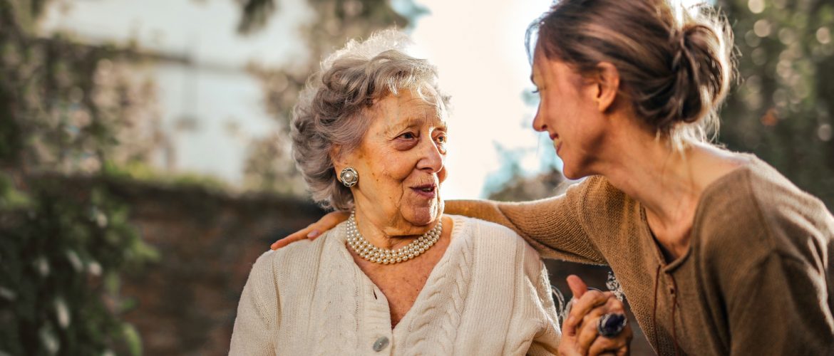 An older woman and a younger woman smile at each other