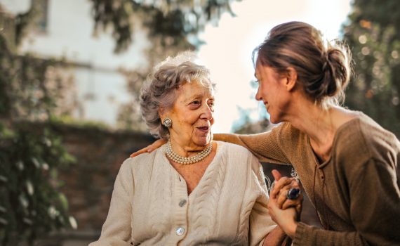 An older woman and a younger woman smile at each other