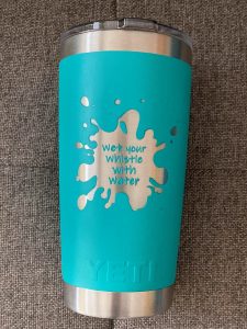 A teal mug with wet your whistle on it