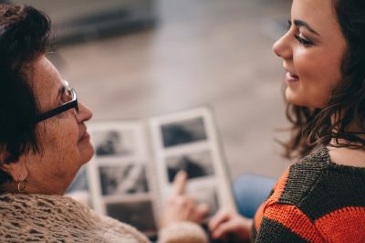 Older adult woman and young woman look through photo album.