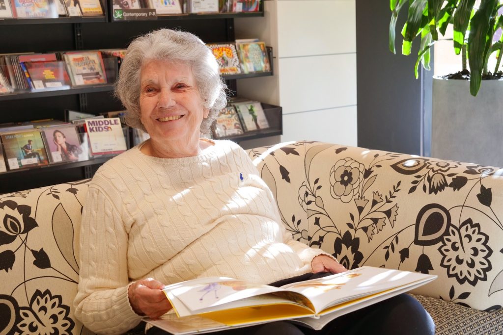 A smiling senior woman with a book opened on her lap