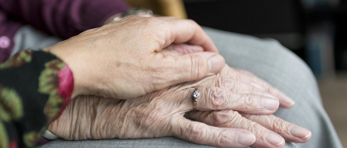 Two sets of elderly hands holding each other