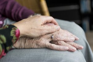 Two sets of elderly hands holding each other