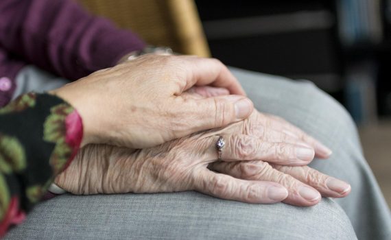 Two sets of elderly hands holding each other