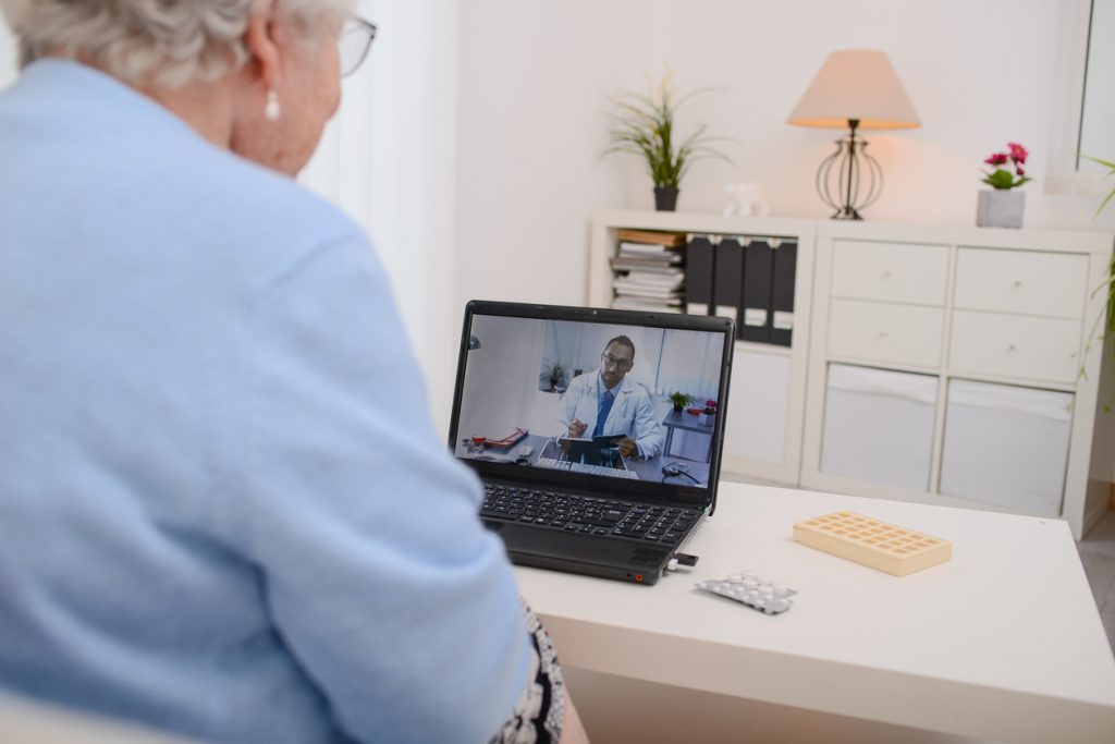 Senior woman connecting to her doctor through a telemedicine consult on her laptop