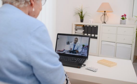 Senior woman connecting to her doctor through a telemedicine consult on her laptop