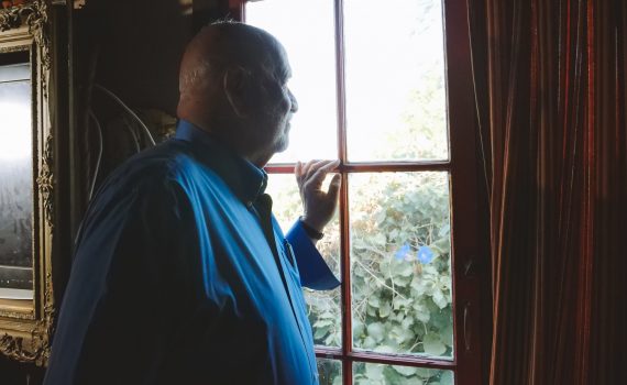 Older adult man looking out of the window