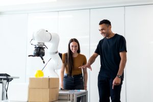 A man and a woman playing with a robot.