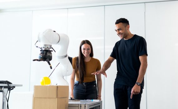 A man and a woman playing with a robot.